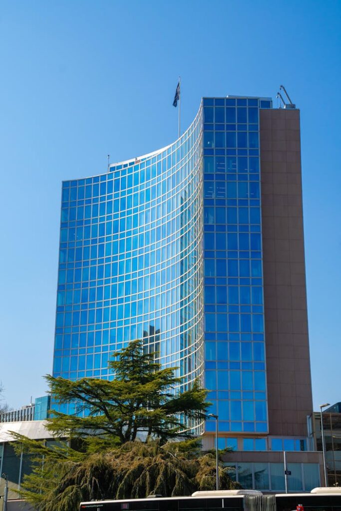 Tall glass building of WIPO reflecting blue sky, a symbol of innovation and intellectual property in Geneva.